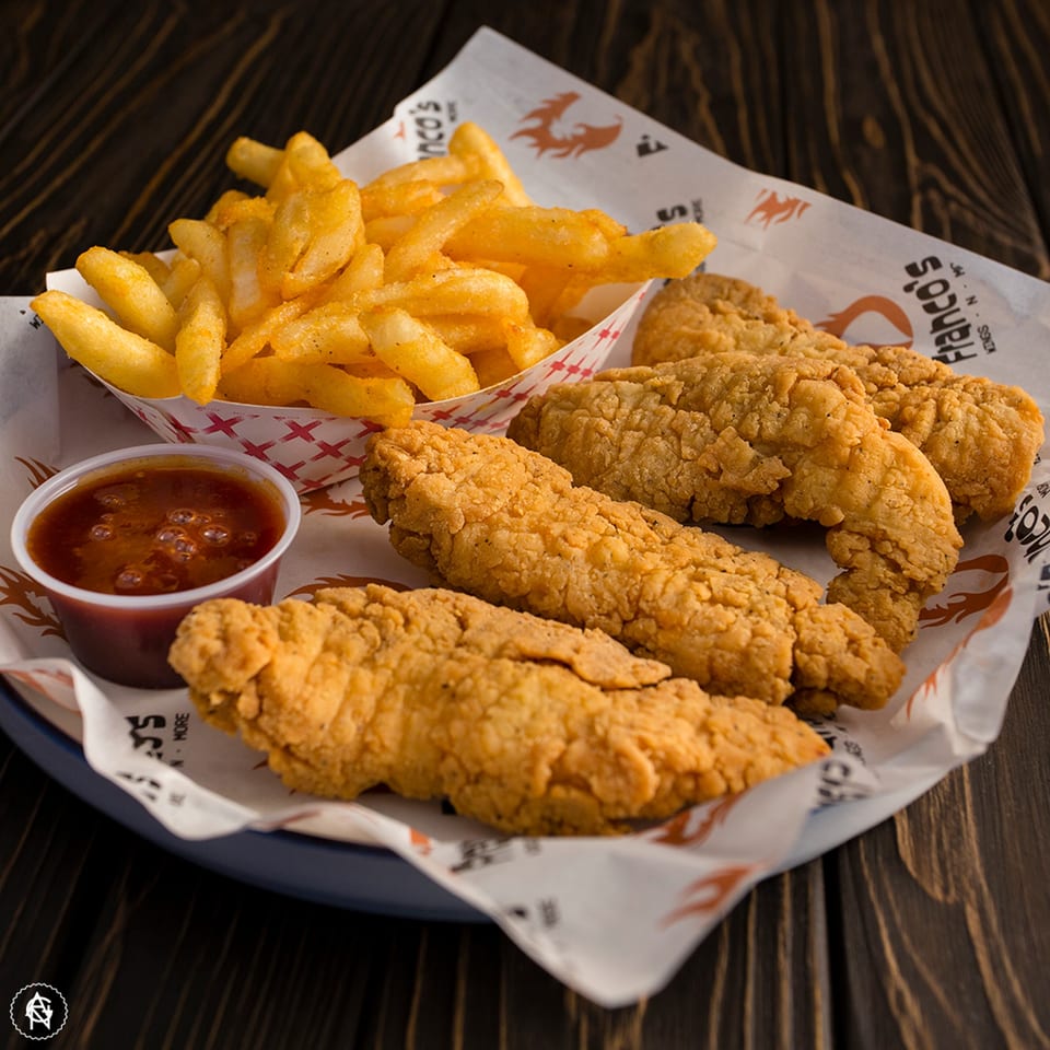 Franco's crispy chicken tenders, golden fries in a paper boat, and a dipping sauce cup.