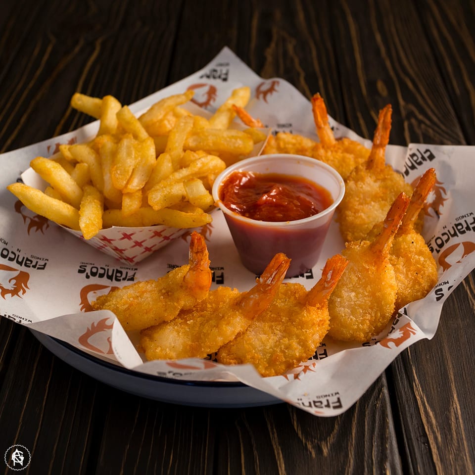 Franco's fried shrimp and french fries with dipping sauce on branded paper.