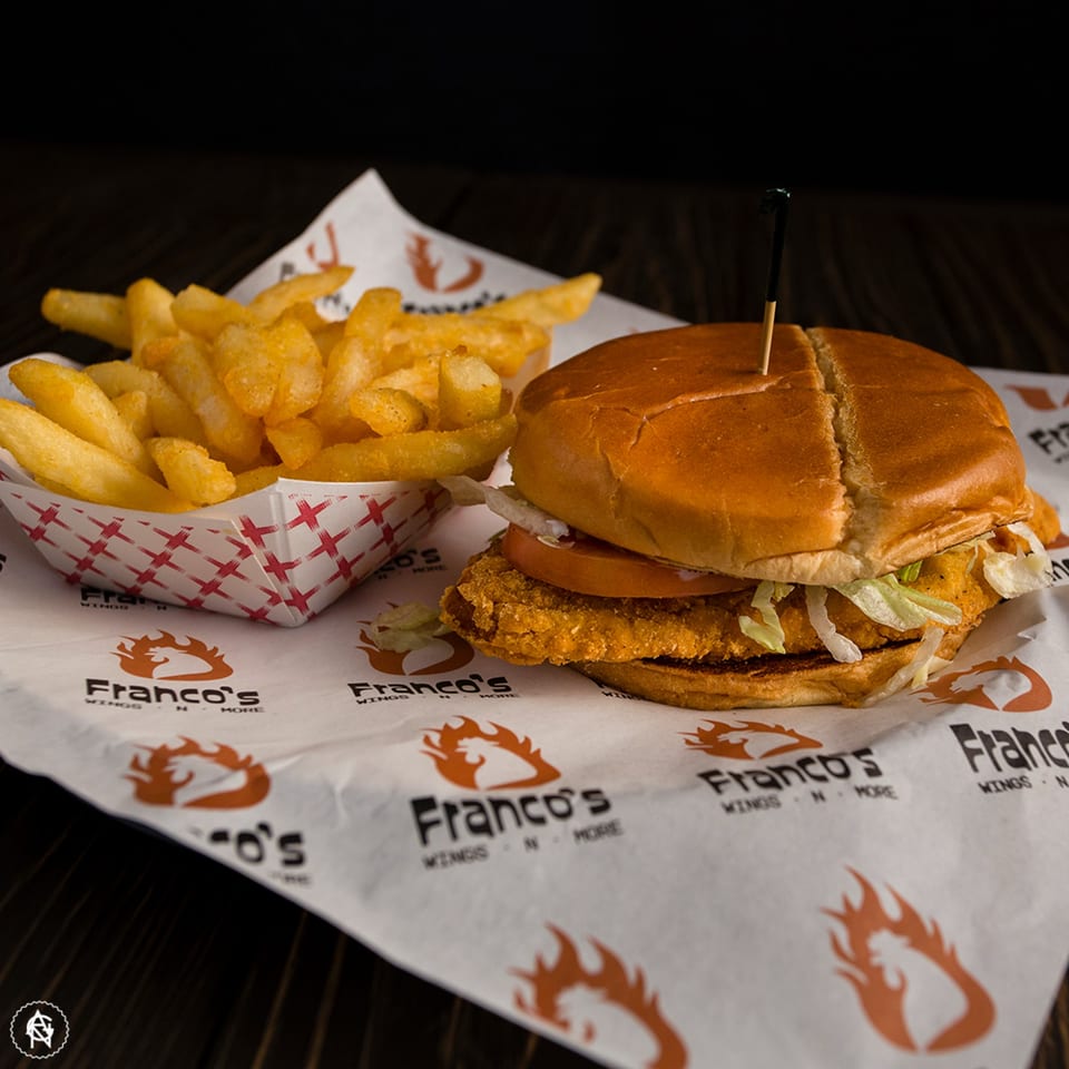 Franco's crispy chicken sandwich with lettuce and tomato, served with a side of fries.
