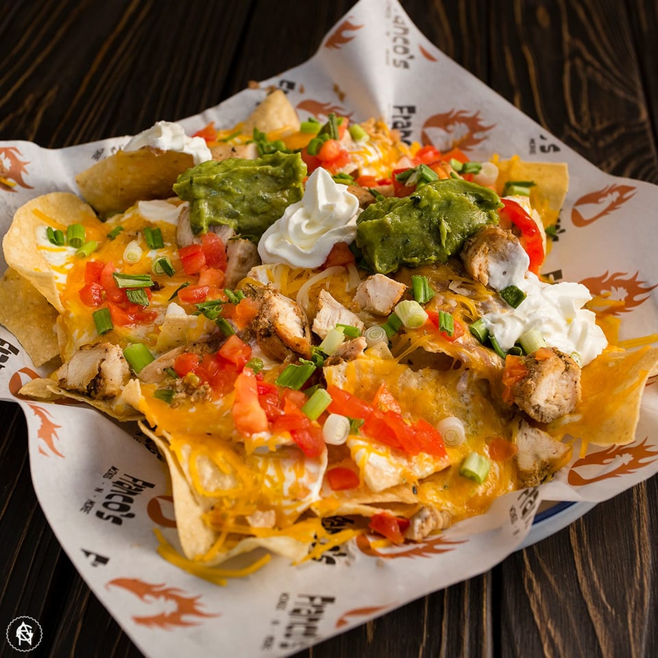 Franco's Wings N More chicken nachos with melted cheese, guacamole, sour cream, tomatoes, and scallions.